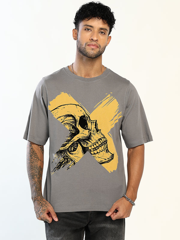 A man wearing a gray crewneck t-shirt with a graphic print of a skull over a yellow paint-stroke 'X' on the front, set against a plain white background.